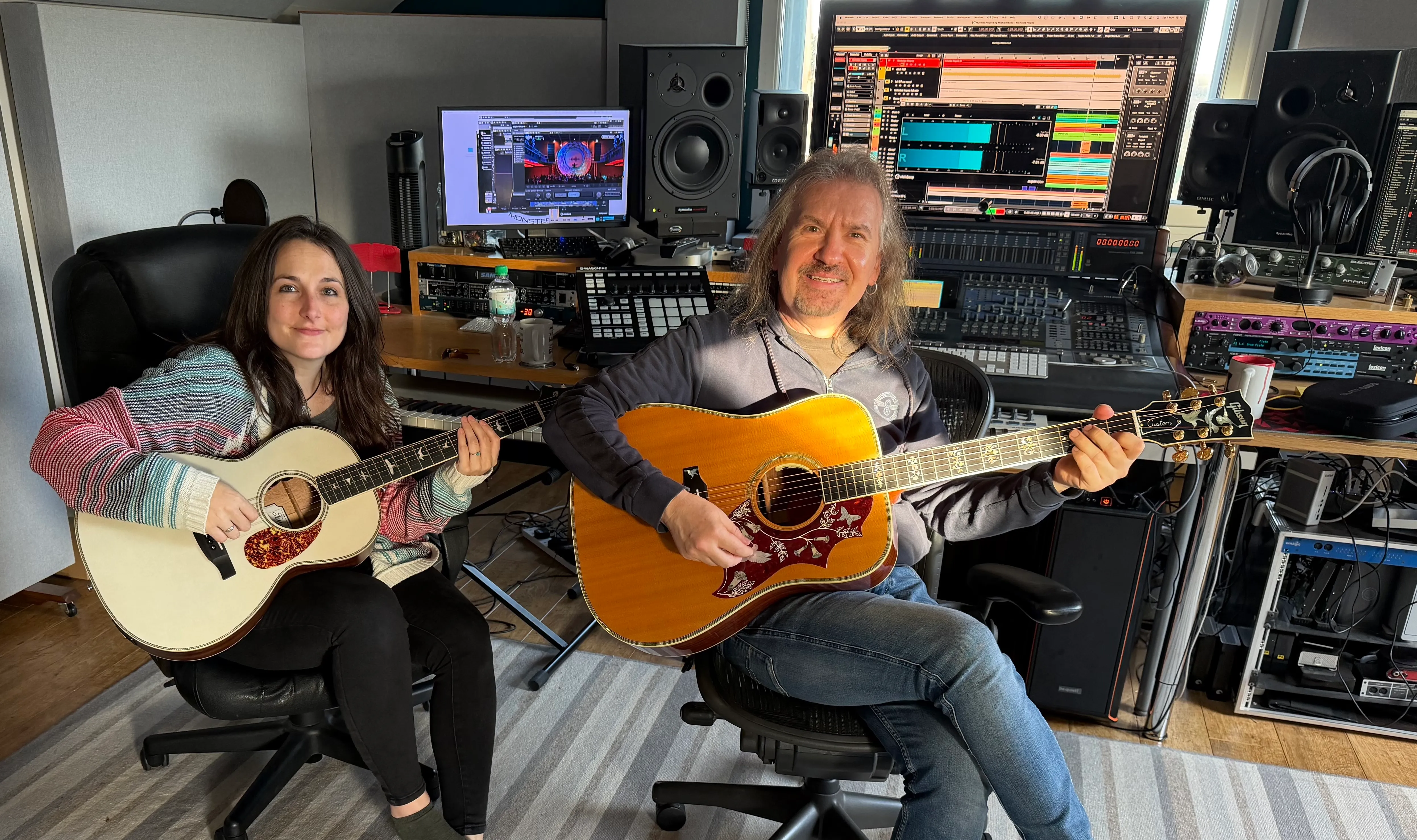 Misha Nikolic collaborating in the studio with an acoustic guitarist surrounded by recording equipment.